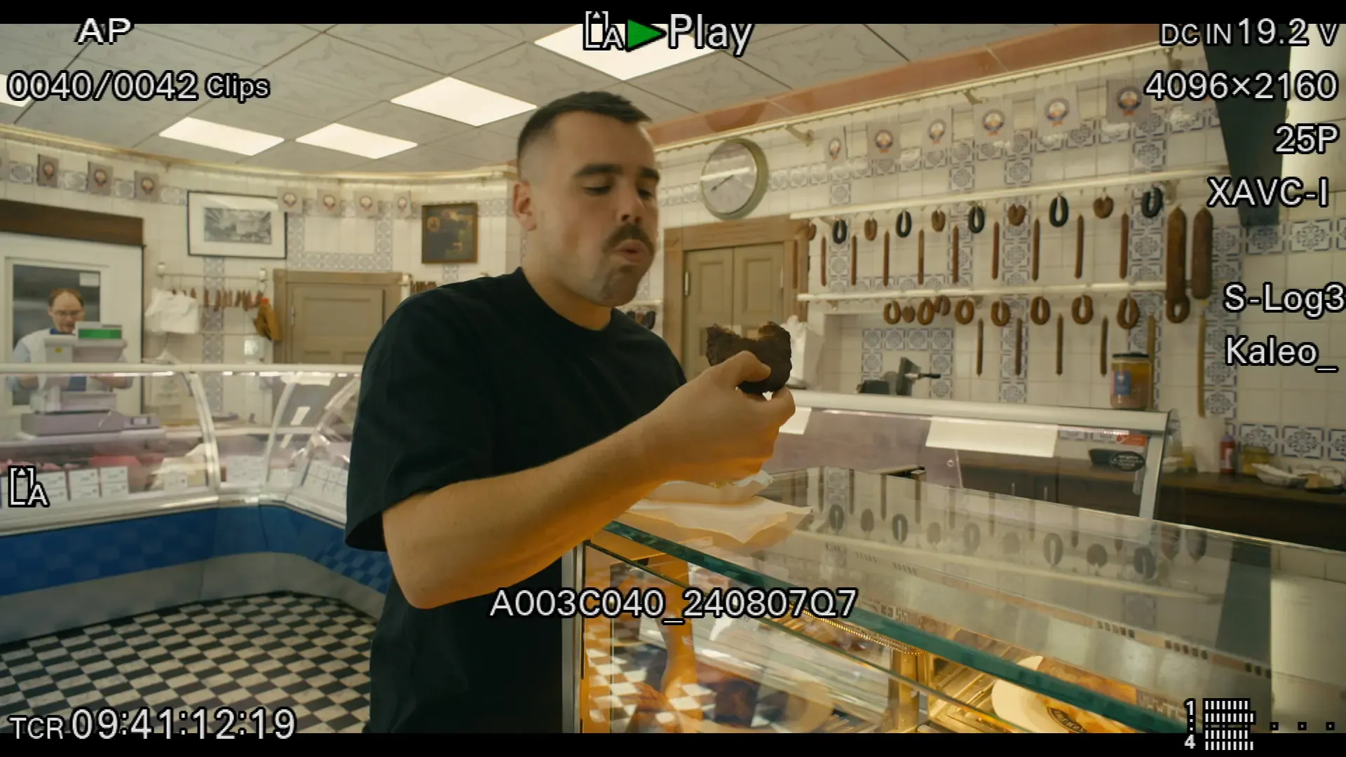 Video Still of Tobias Beck inside of a traditional butcher shop tasting a meat ball.