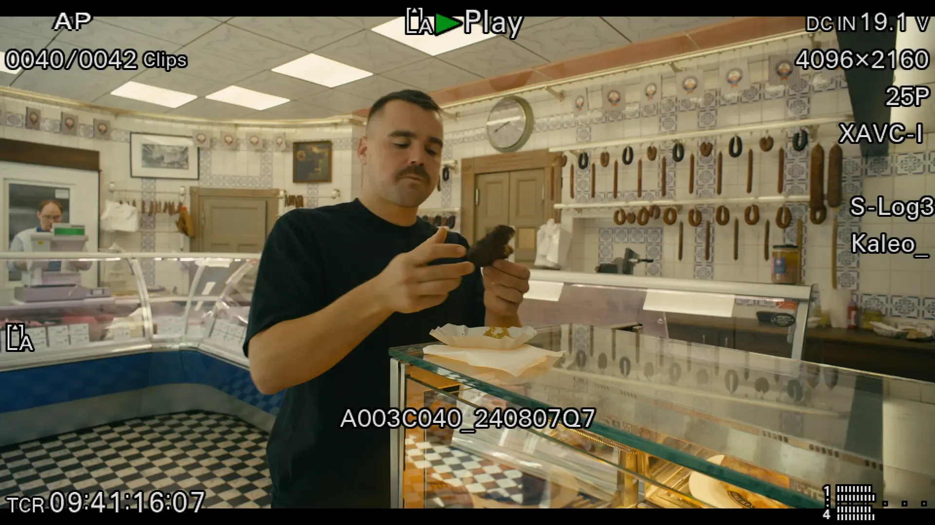 Video Still of Tobias Beck inside of a traditional butcher shop tasting a meat ball.